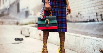 Fashion-forward outfit with plaid skirt and colorful handbag in urban setting.