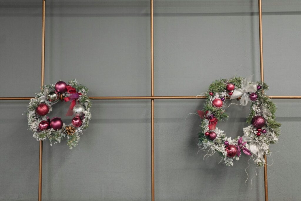 Two decorative Christmas wreaths with baubles on a stylish modern wall, adding festive charm.
