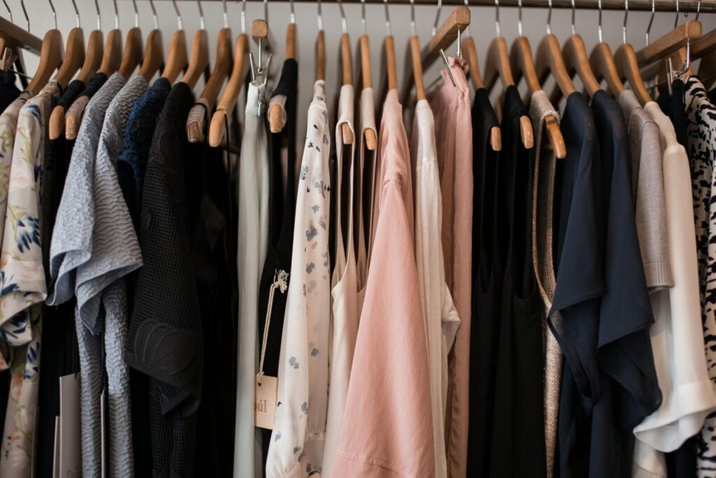 A stylish collection of women's clothing hanging on wooden hangers in a boutique setting.