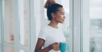 Woman holding mug looking out window