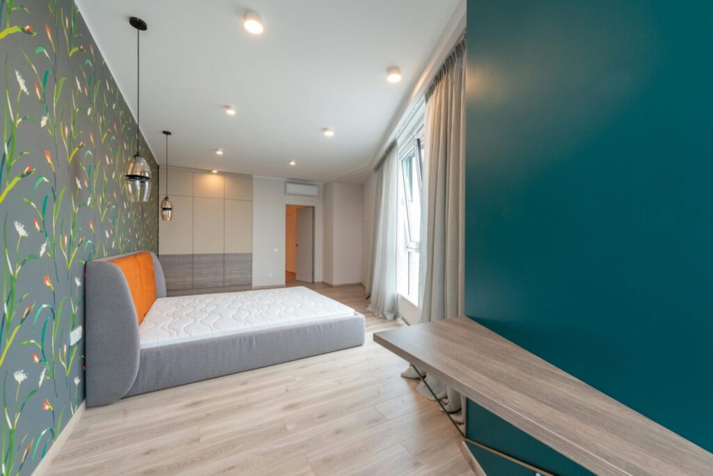 Contemporary bedroom interior featuring vibrant floral wallpaper and minimal furniture.