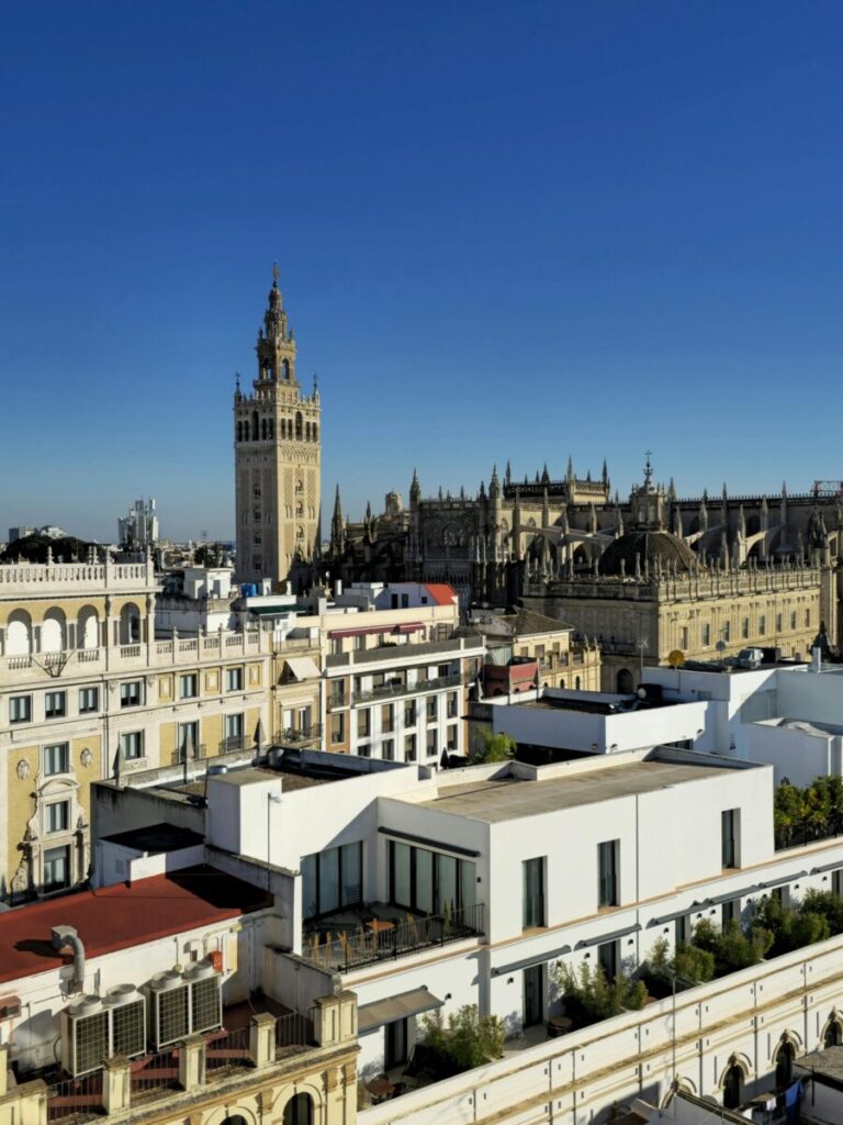Stunning aerial shot of Seville Cathedral and La Giralda Tower under a clear blue sky in Seville, Spain.