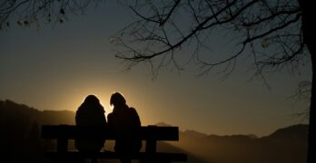 silhouette of 2 person sitting on bench during sunset