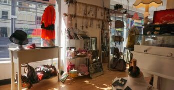 A well-lit vintage boutique showcasing clothing, bags, hats, and accessories.