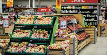 Colorful produce aisle in a supermarket showcasing fresh apples with discount signage.