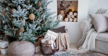 Elegant Christmas tree with rustic decor in a cozy living room setting.