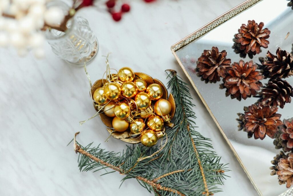 Festive Christmas decorations featuring golden baubles and pinecones on a reflective surface.