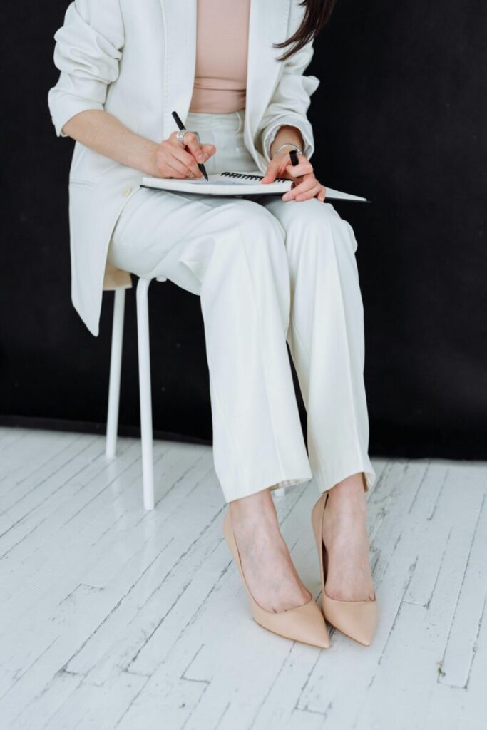 Stylish woman in business attire sits writing with focus and elegance.
