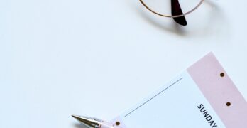 eyeglasses near paper and ballpoint pen