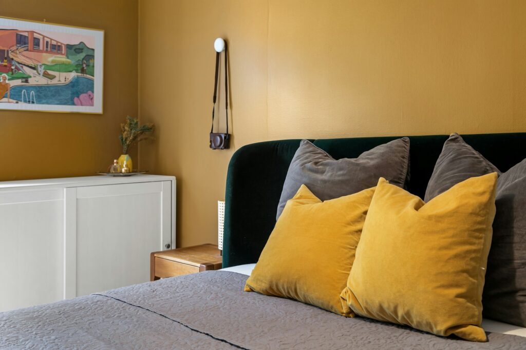 A bed with yellow and gray pillows in a bedroom