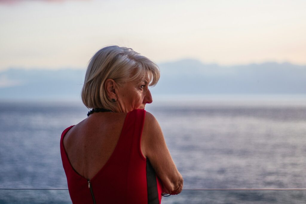 a woman in a red dress looking out at the ocean