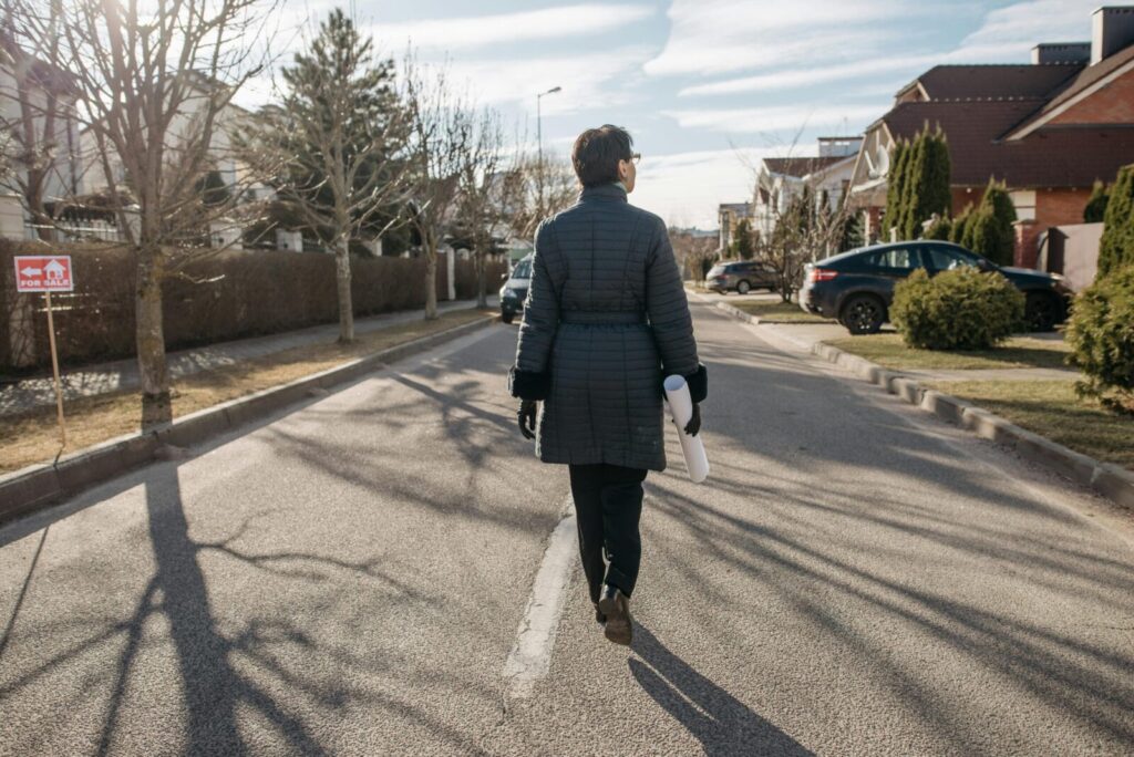 Back view of a woman walking down a suburban street on a sunny winter day.