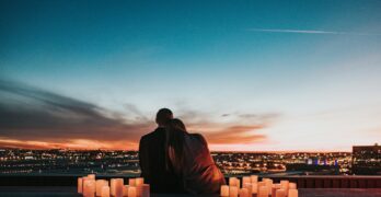 couple sitting on the field facing the city