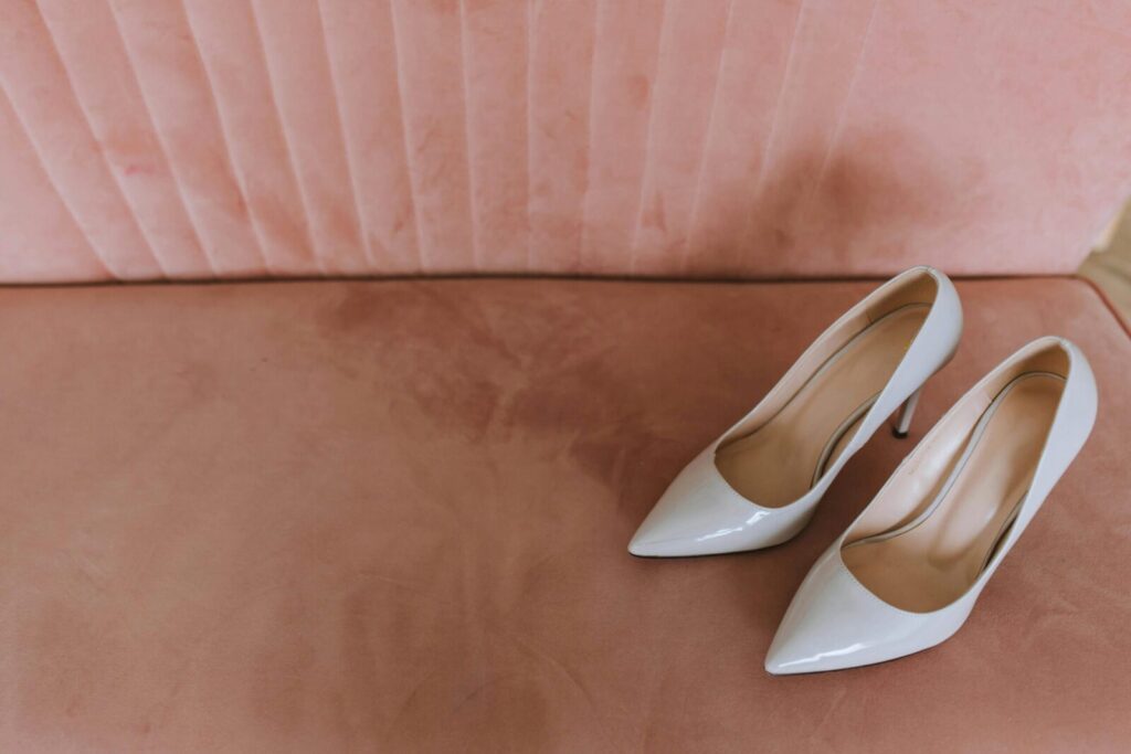 White high heels elegantly placed on a plush pink sofa with a stylish top view.