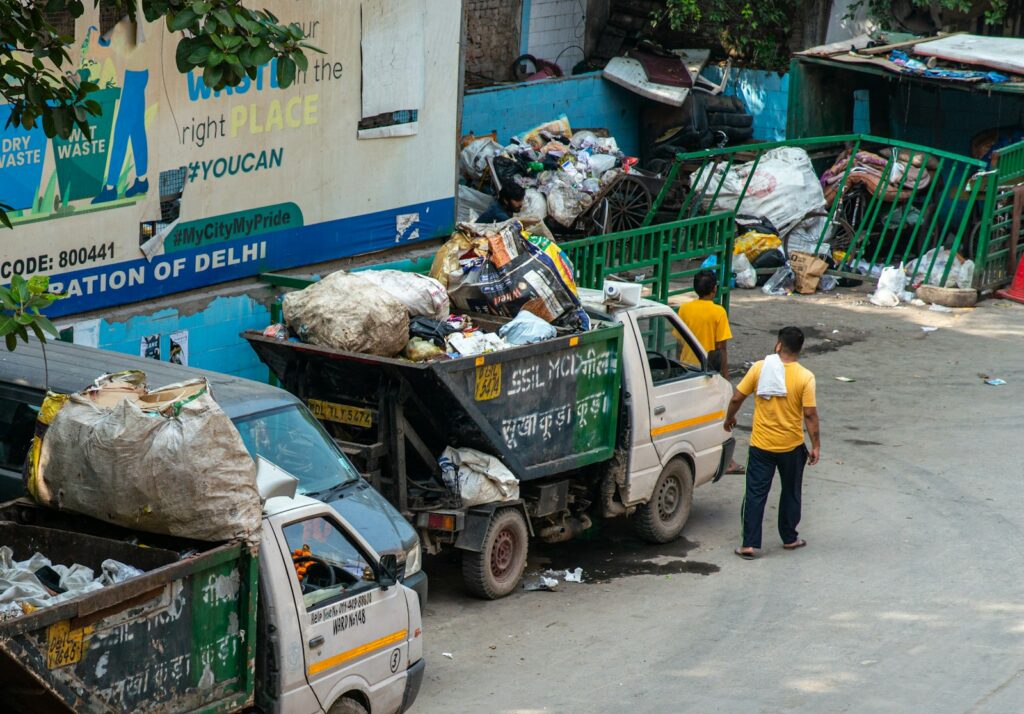 Workers loading trash onto trucks near a building.