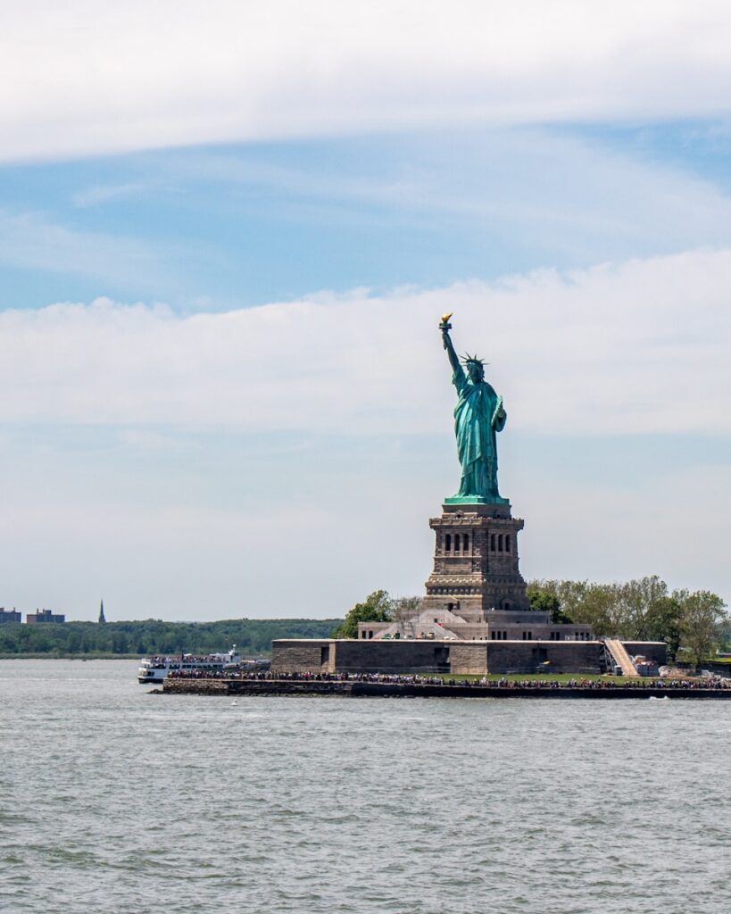 The statue of liberty is in the middle of the water