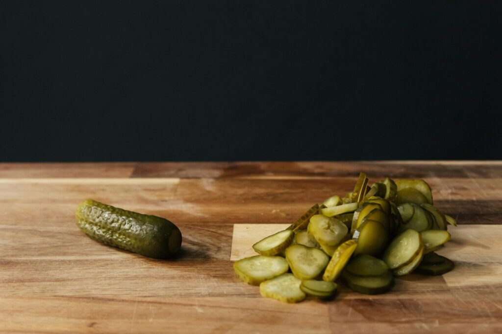 Sliced pickles on a wooden board with rustic background, highlighting freshness and simplicity.