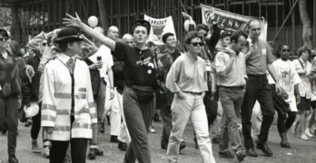grayscale photo of people walking beside house