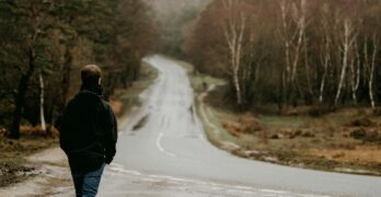 man in black jacket walking on road during daytime