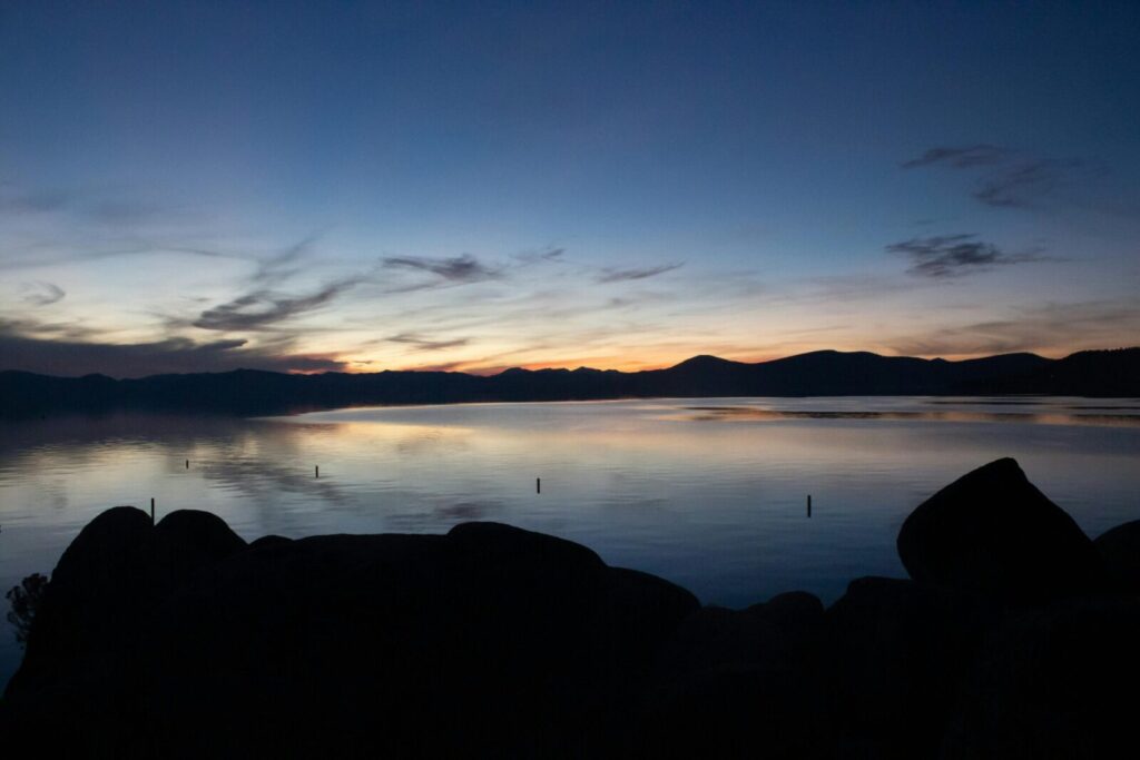 Calm waters and silhouetted mountains at twilight over Lake Tahoe, a perfect nature scene.