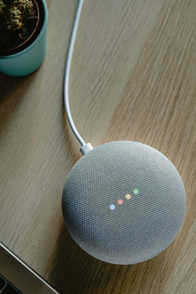 A top view of a smart speaker with a glowing indicator on a desk, emphasizing modern technology.