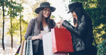 Two women looking into shopping bags outdoors