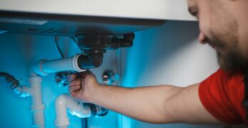 a man working on a pipe in a wall