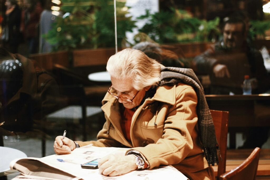 man in brown coat writing on white paper