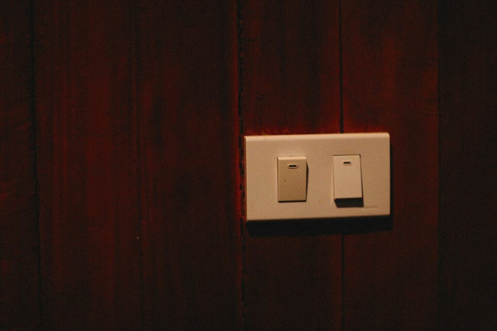 a white light switch sitting on top of a wooden wall