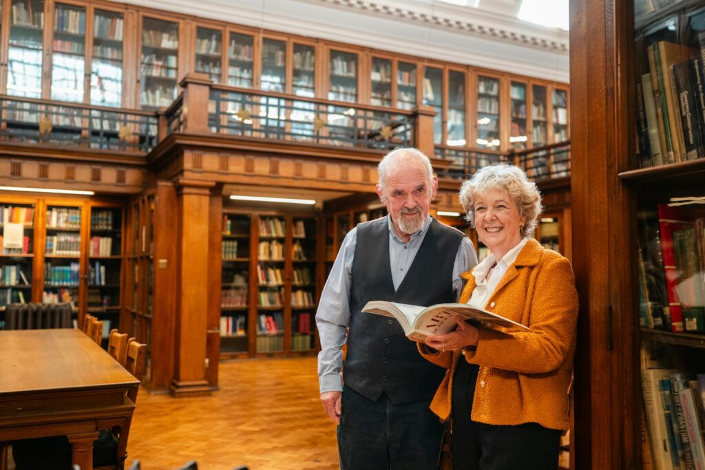 Elderly couple holding a book in a library