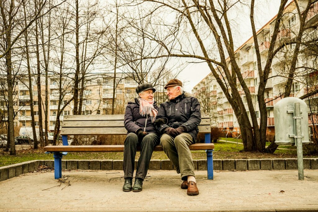 Elderly couple happily sitting on a bench together.