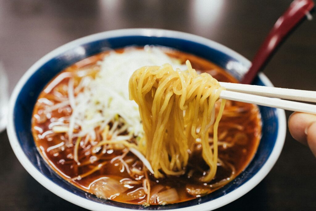 A person holding chopsticks over a bowl of noodles