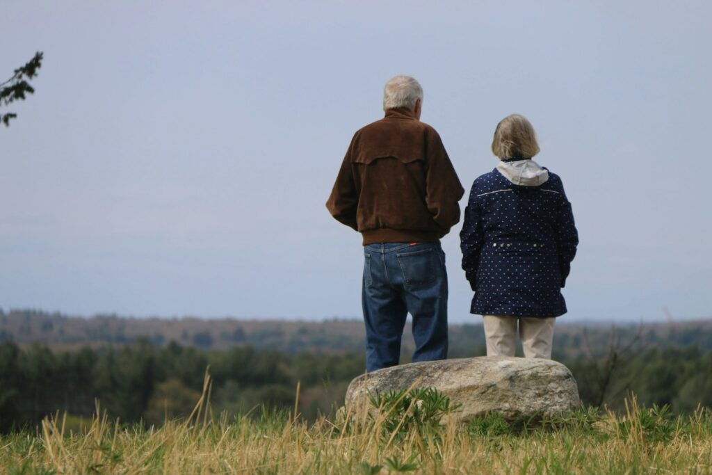 a man and woman standing on a rock overlooking a forest