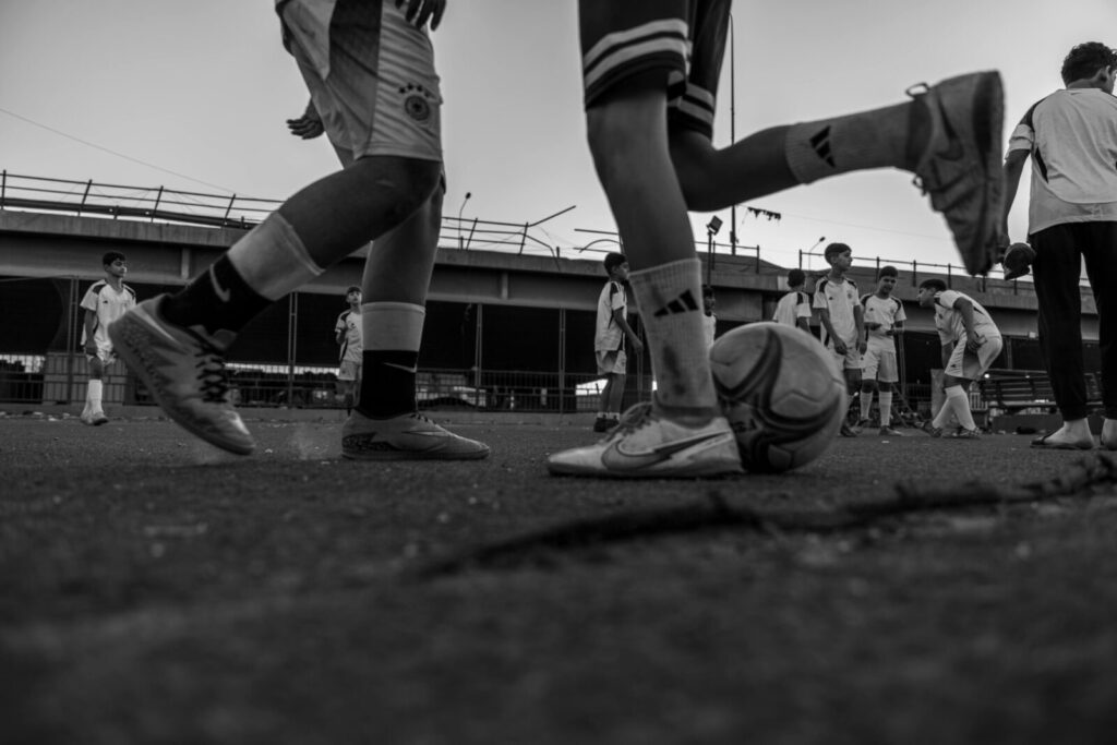 Black and white image of children playing soccer outdoors, showcasing teamwork and energy.